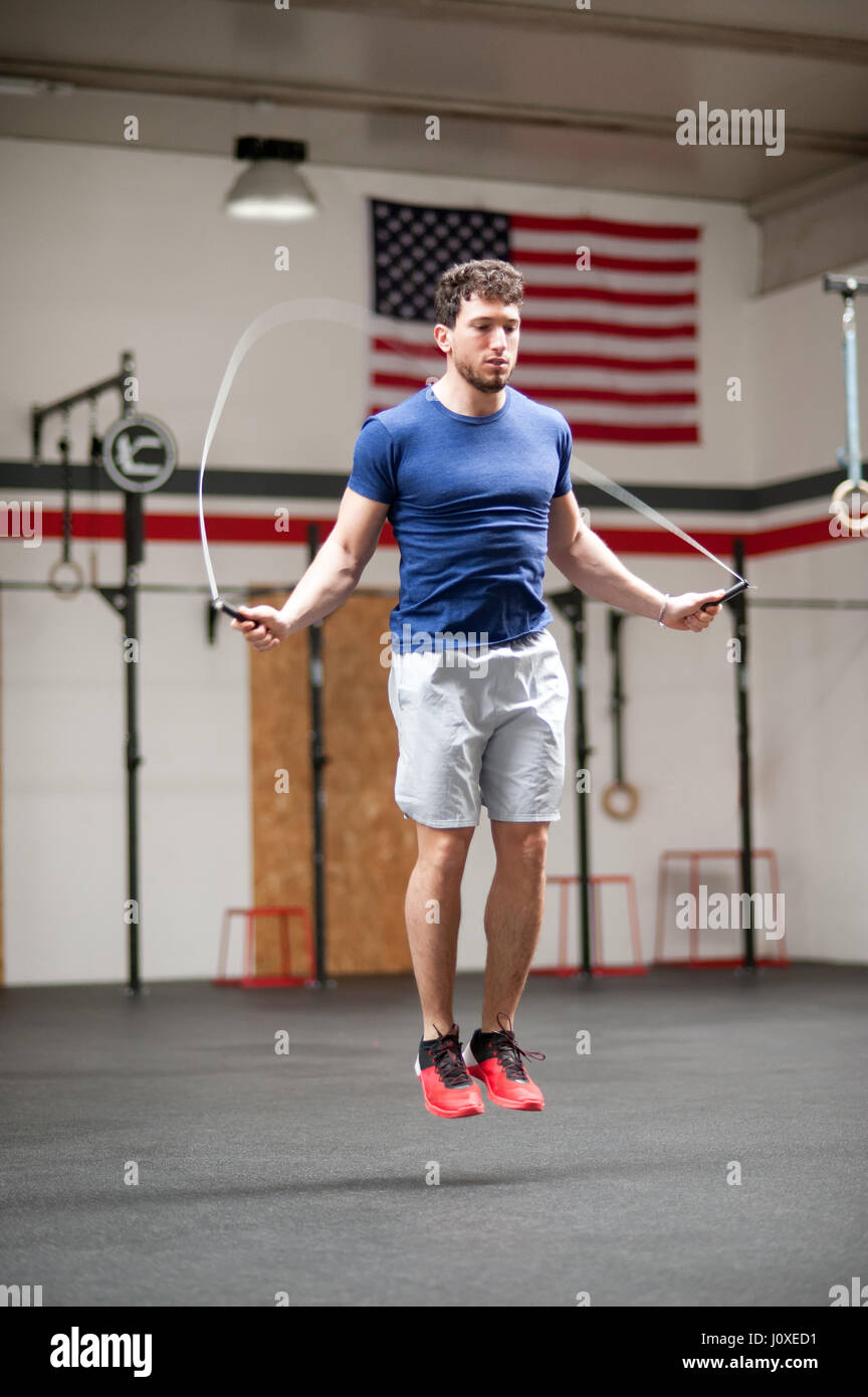 Montare athletic giovane uomo utilizzando una corda da salto per allenamento in palestra crossfit jumping midair in una salute e concetto di fitness Foto Stock