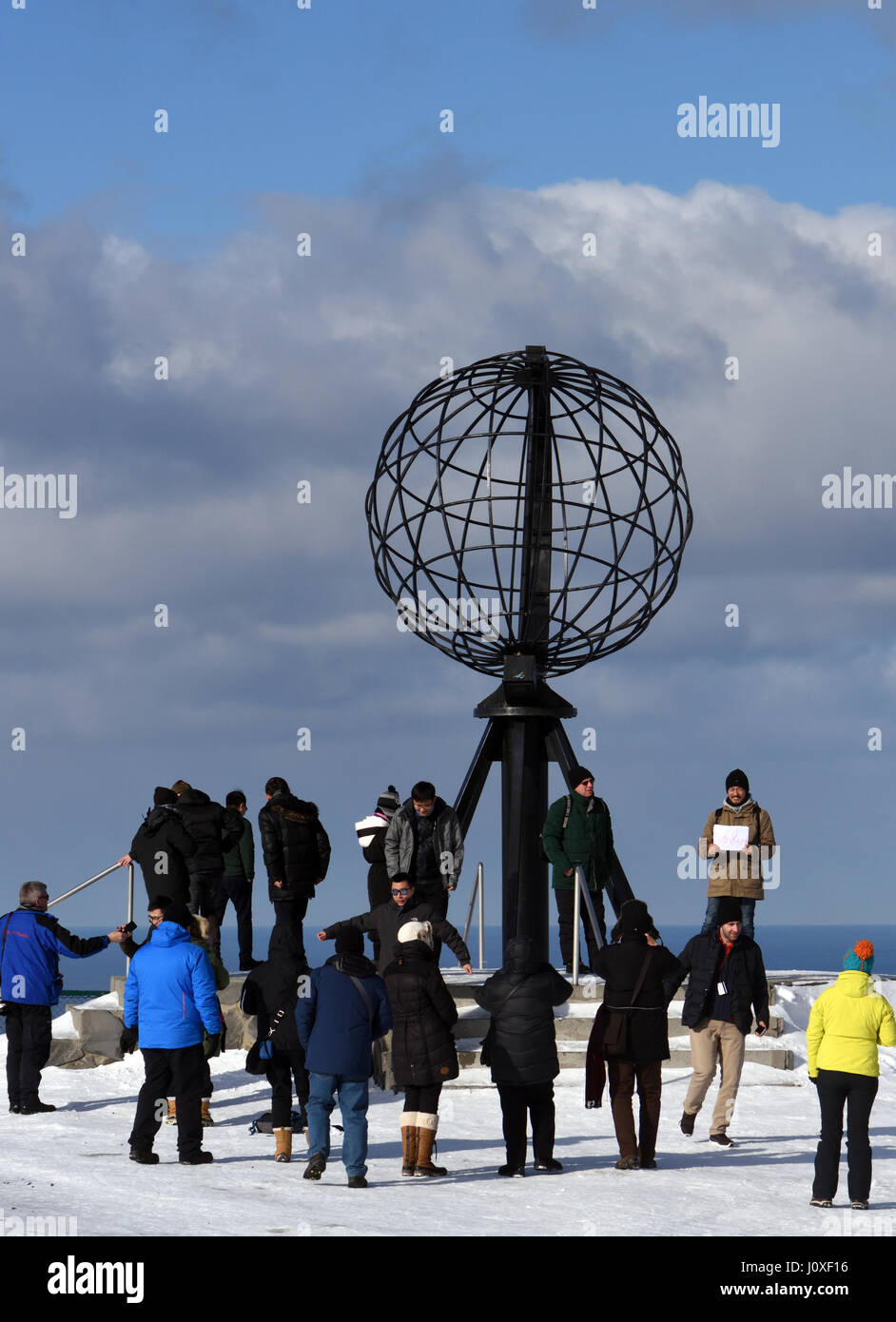 Turisti si riuniscono attorno al globo monumento su Capo Nord, Nordkapp. Nordkapp, Finmark, Norvegia. Foto Stock