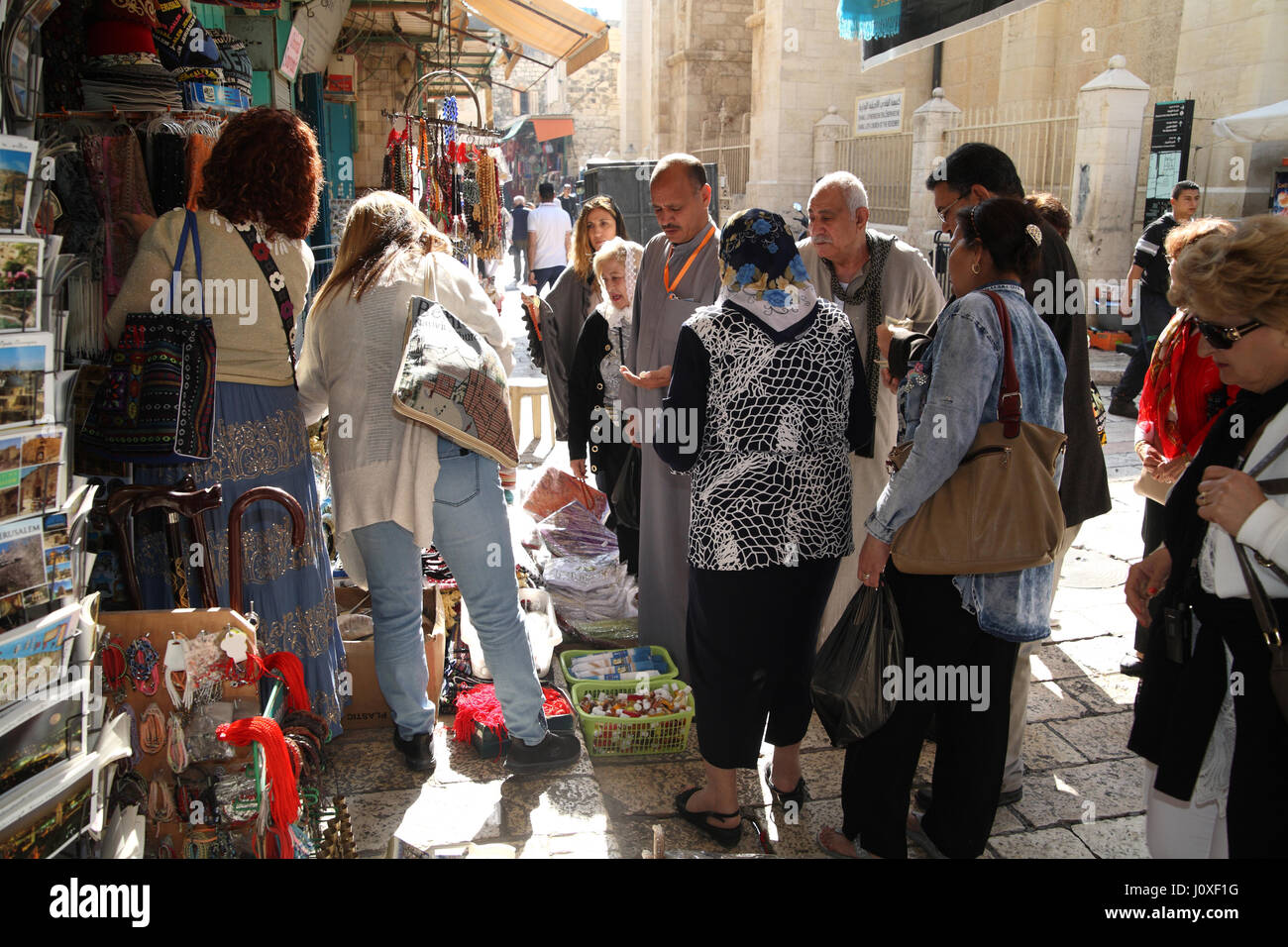 Dark scuoiate copta egiziana di persone e biondo le donne greche, Christian i pellegrini e i turisti guardano un cristiano reliquie e negozio di souvenir shop, vecchia di Gerusalemme. Foto Stock
