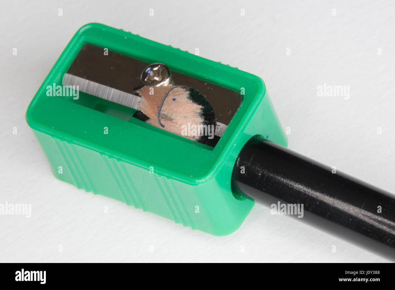 Green temperamatite con una matita nera su sfondo bianco Foto Stock