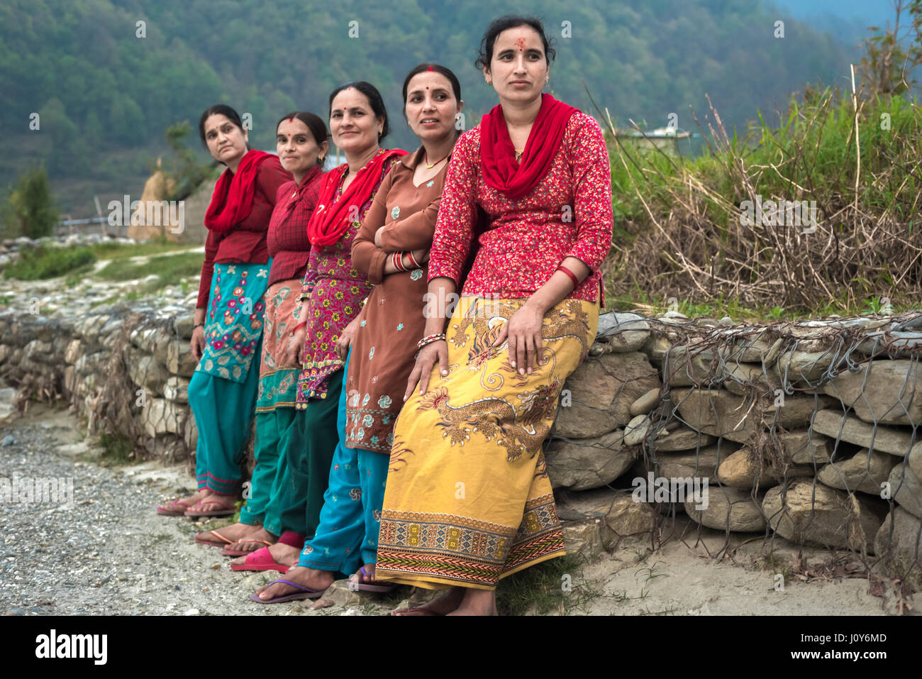 Ritratto di donne, abitanti di Khahare, in quanto si trovano vicino a un muro di gabione sul lato della pianura alluvionale di Harpan Khola a Kaski, Gandaki, Nepal. Foto Stock