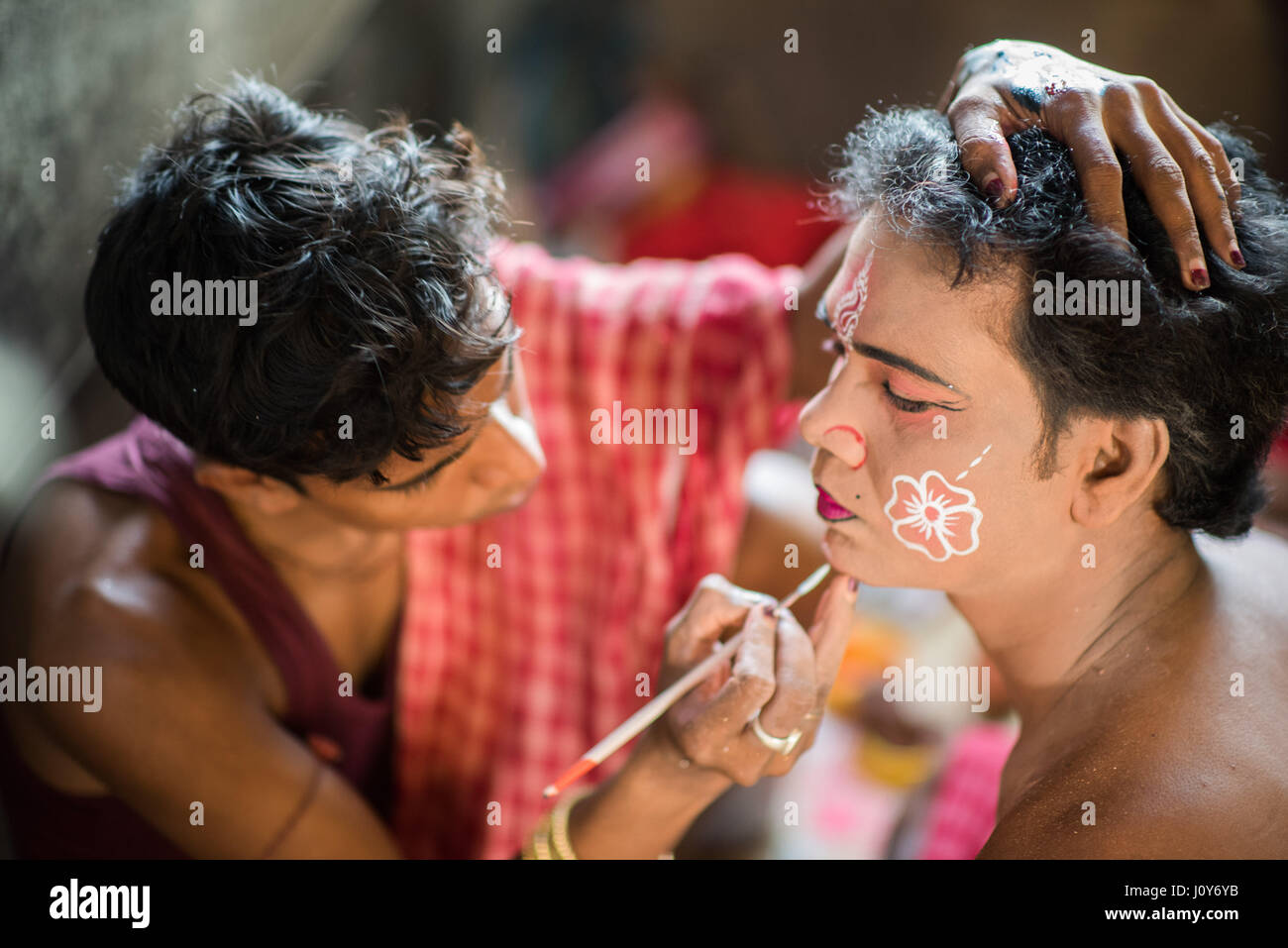 Giovane maschio indiano avente il suo volto dipinto prima del Gajan festival di Krishnadepur, Bengala occidentale Foto Stock
