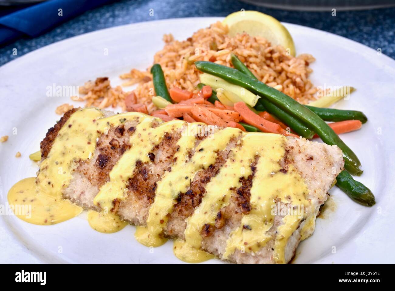 Grigliata di mahi-mahi spruzzata con salsa cremosa servita con un lato di riso e verdure miste Foto Stock