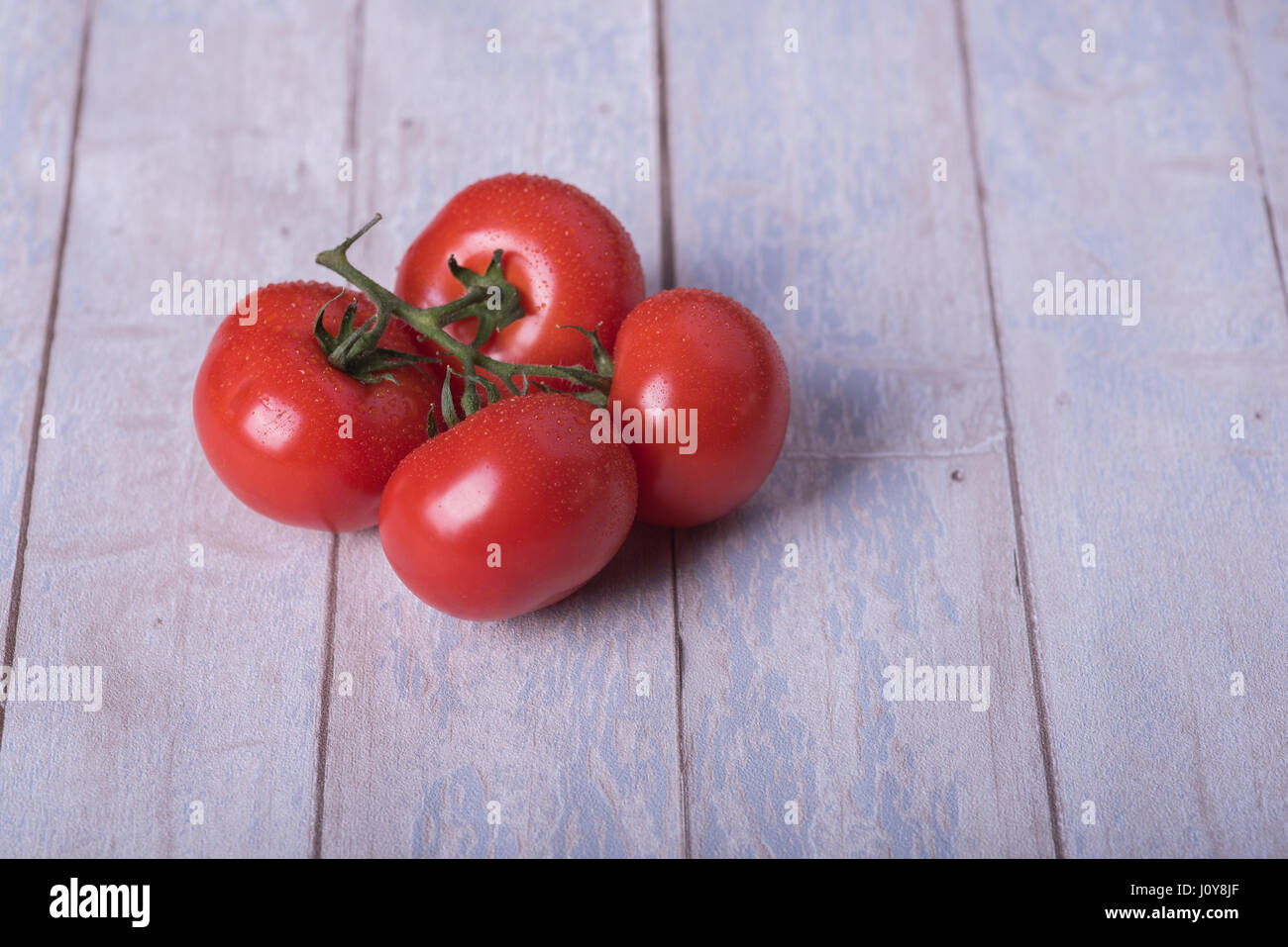 Pomodori freschi con verde su un tavolo di legno Foto Stock