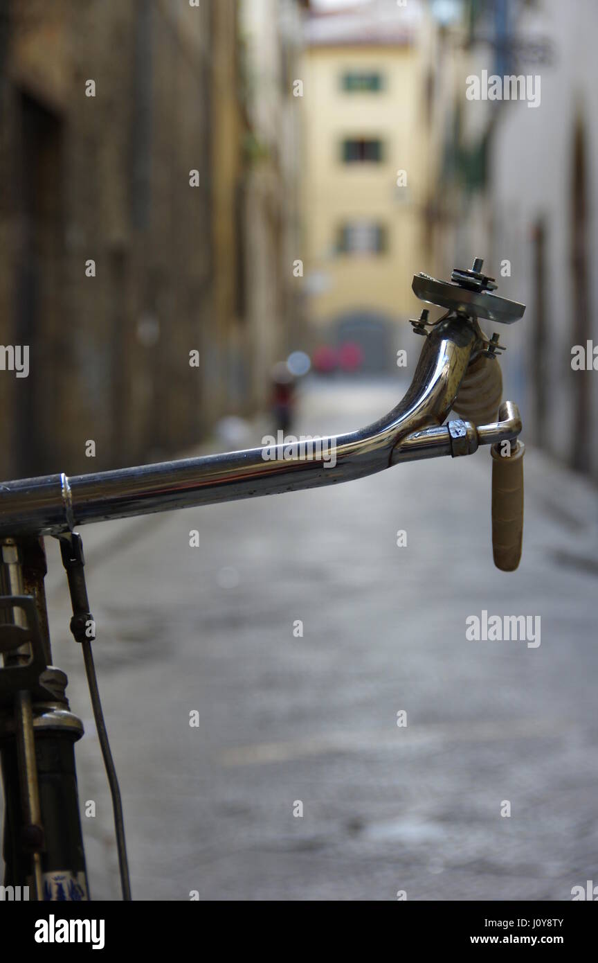 Manubrio di bicicletta dettaglio contro un bokeh Vicolo nel centro di Firenze (Firenze), Toscana, Italia, Europa - il fuoco selettivo sul manubrio Foto Stock