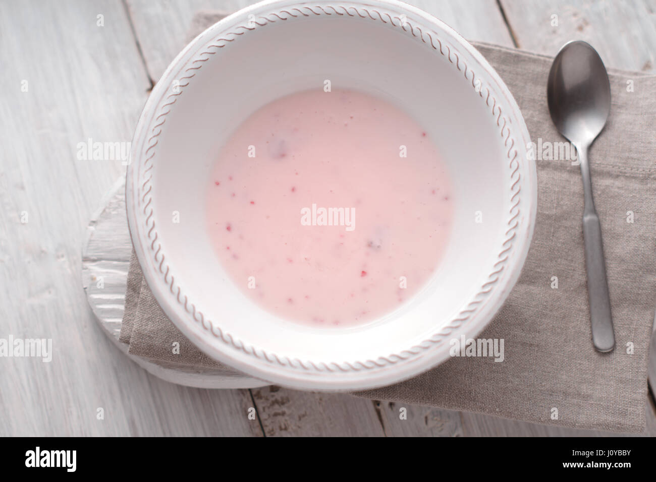 Yogurt alla frutta nella piastra bianca sul bianco tavolo in legno vista superiore Foto Stock