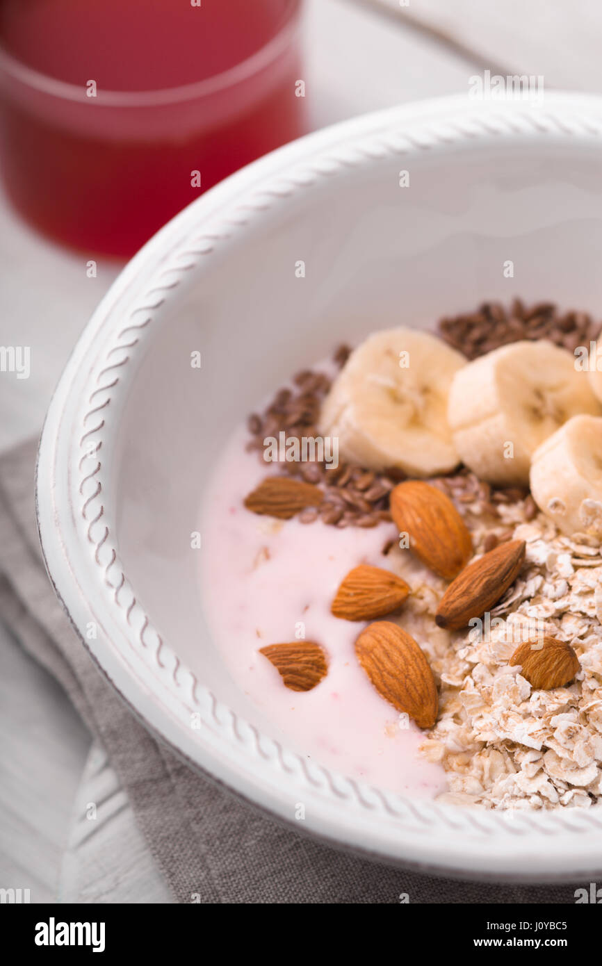 Yogurt alla frutta con diversi condimenti sul bianco tavolo in legno Foto Stock