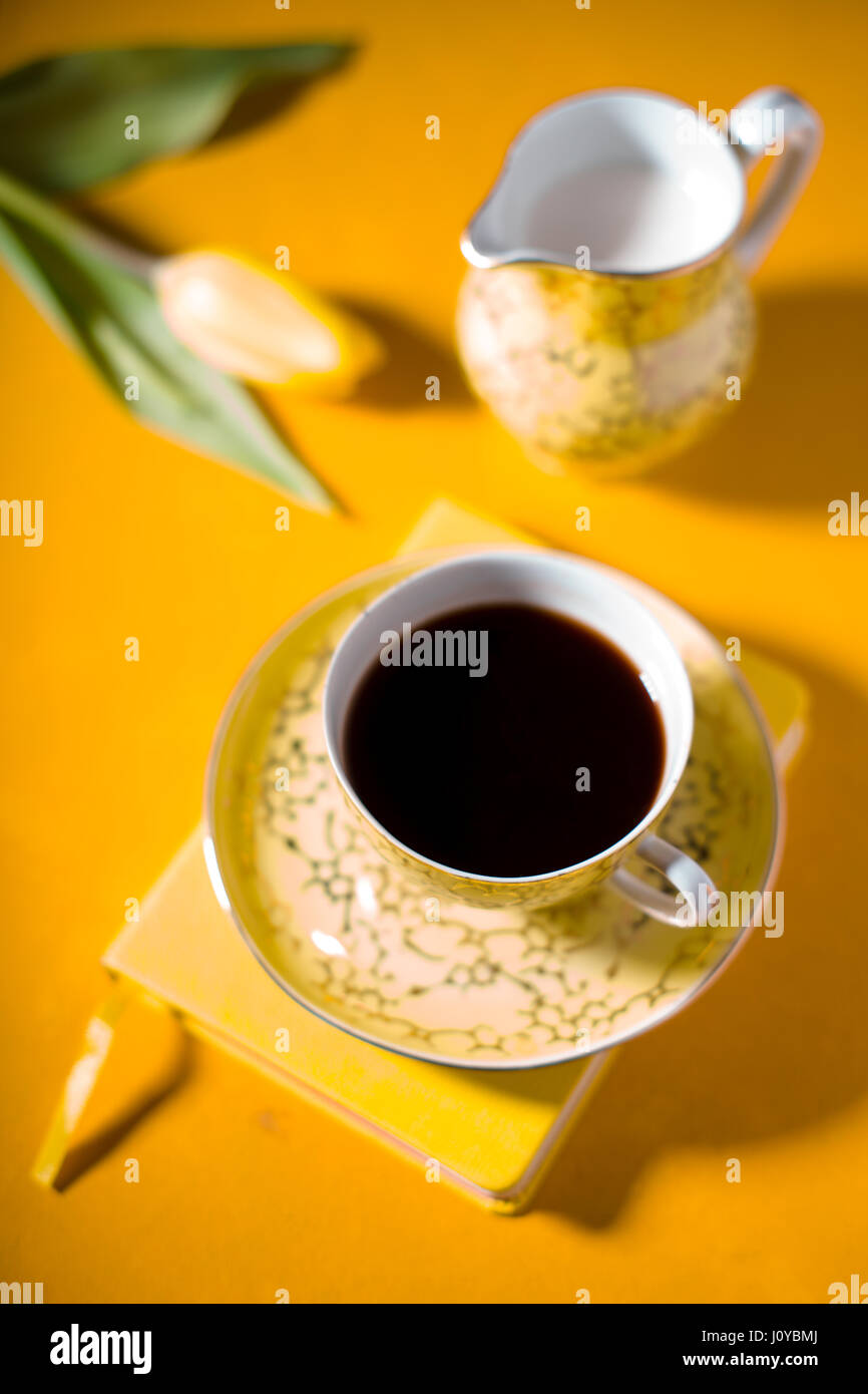 Tazza di caffè, notebook, tulip su sfondo giallo Foto Stock
