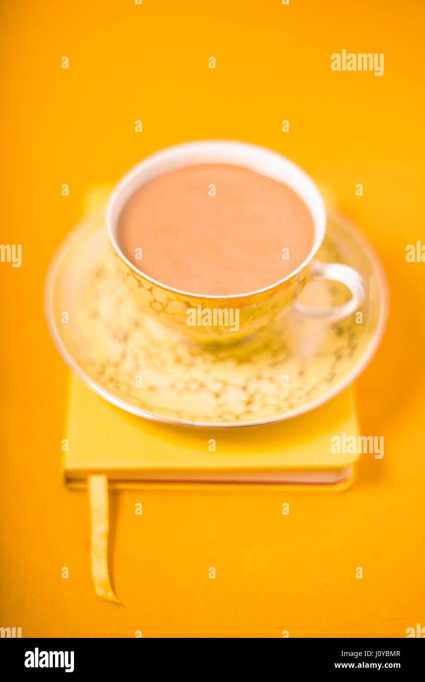 Tazza e piattino e caffè con latte su sfondo giallo Foto Stock