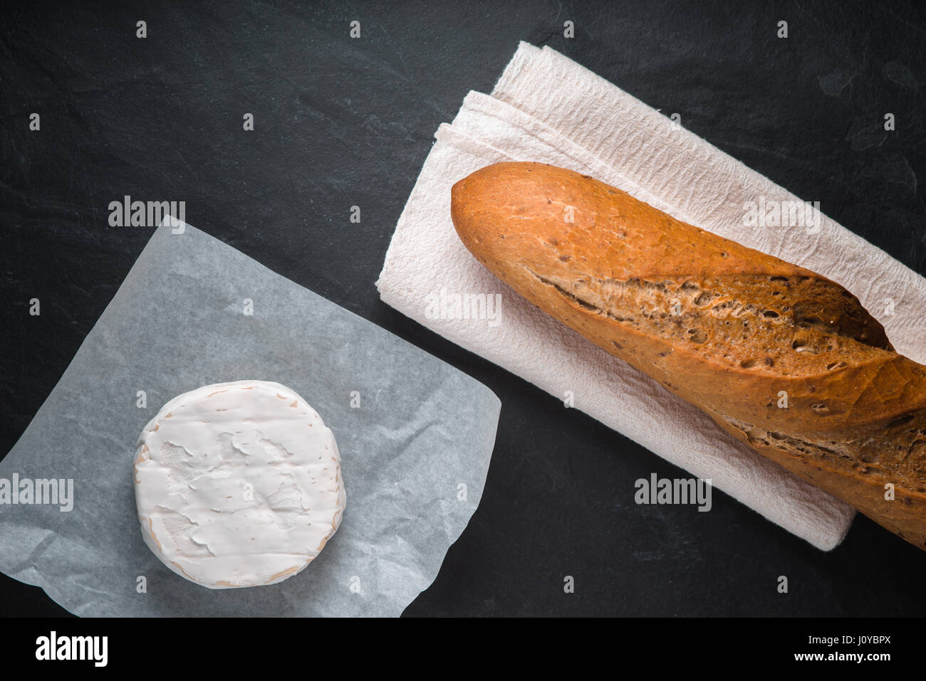 Formaggio Brie e baguette al buio su un tavolo Foto Stock