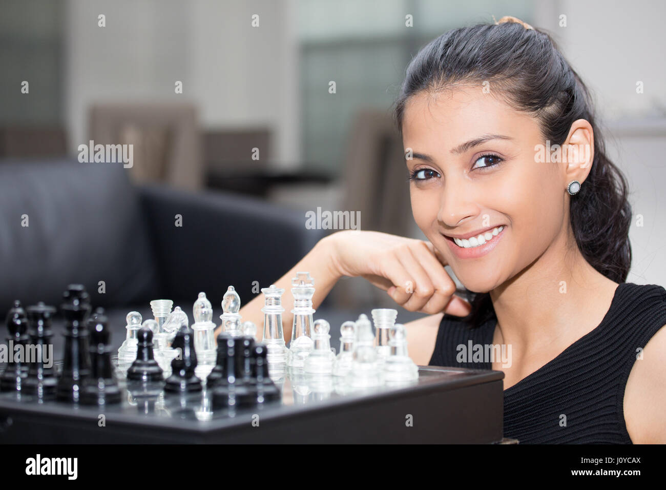 Closeup ritratto, pensando che la donna in camicia nera giocando a scacchi, chiedendo la prossima mossa, isolato sfondo interni Foto Stock