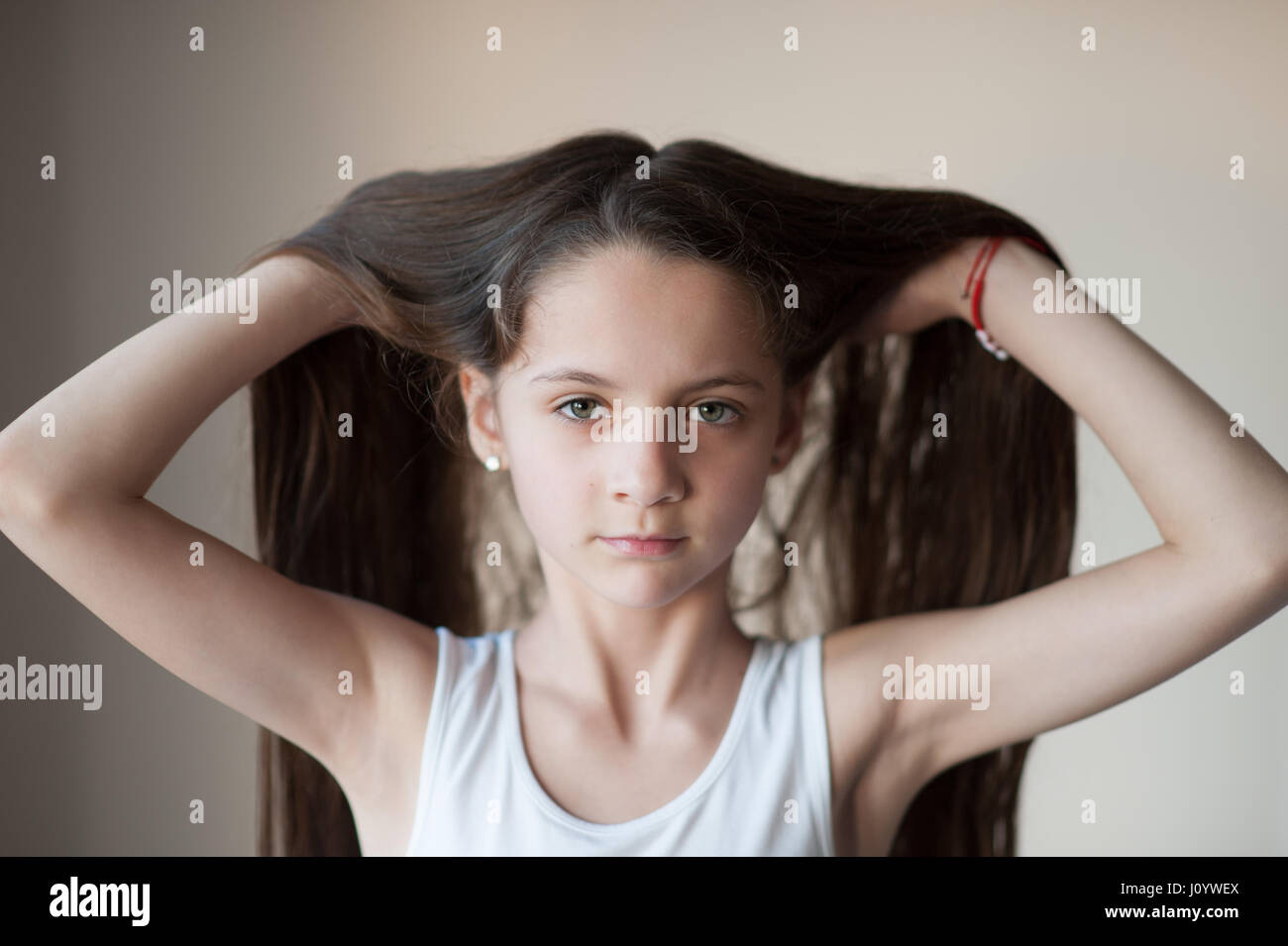 Giovane e bella ragazza in un T-shirt sollevando i capelli con due mani Foto Stock