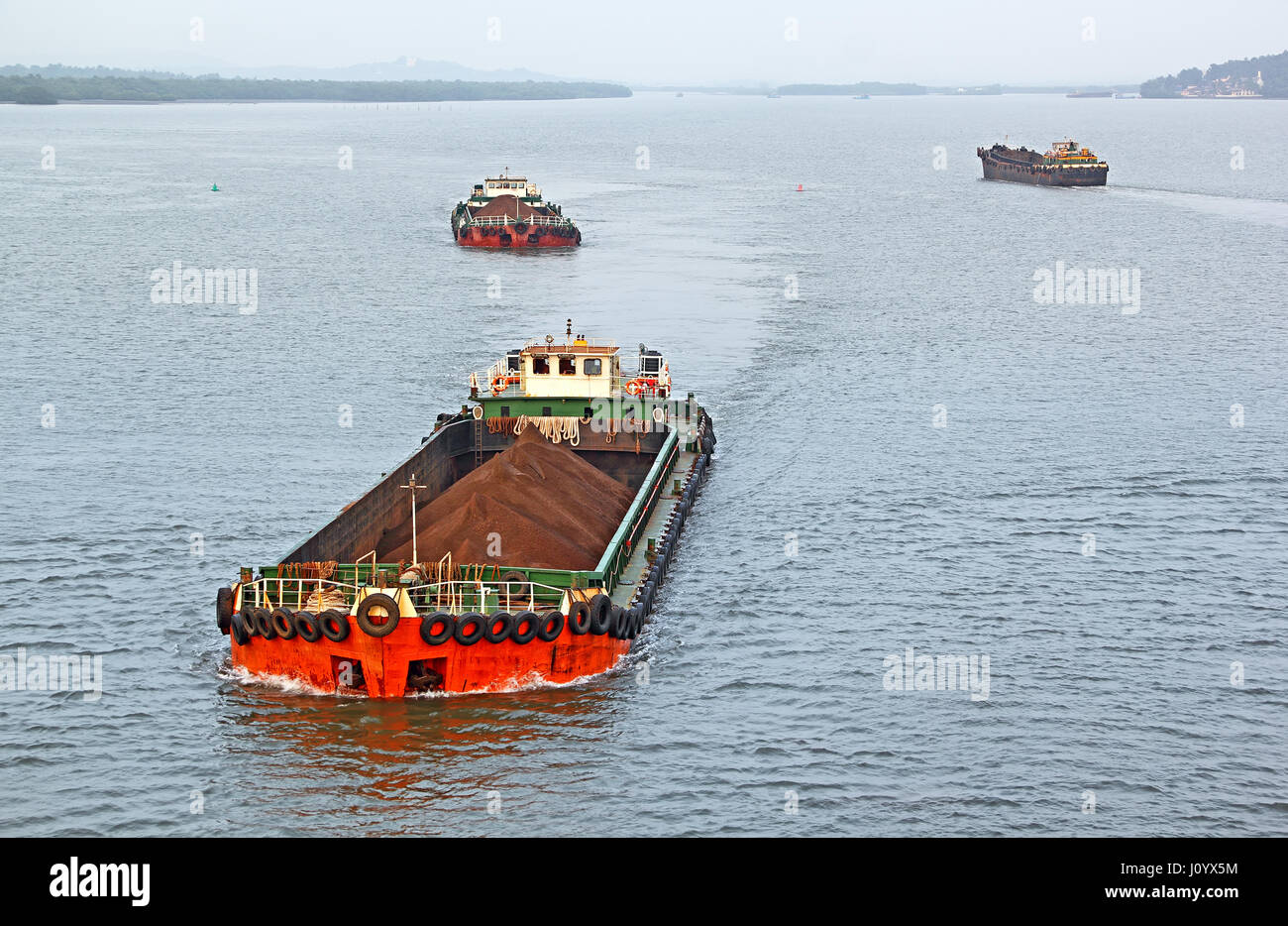 Grandi bettoline il trasporto del minerale di ferro estratto nell'entroterra per il porto principale per il caricamento in grandi navi per esportazione, lungo il Fiume Mandovi in Goa. Foto Stock