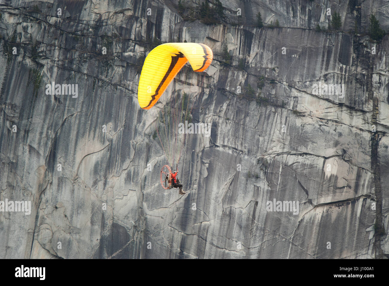 Un uomo vola un parapendio motorizzato o para motore oltre il Capotribù Stawamus e Cascate Shannon. Squamish BC, Canada. Foto Stock