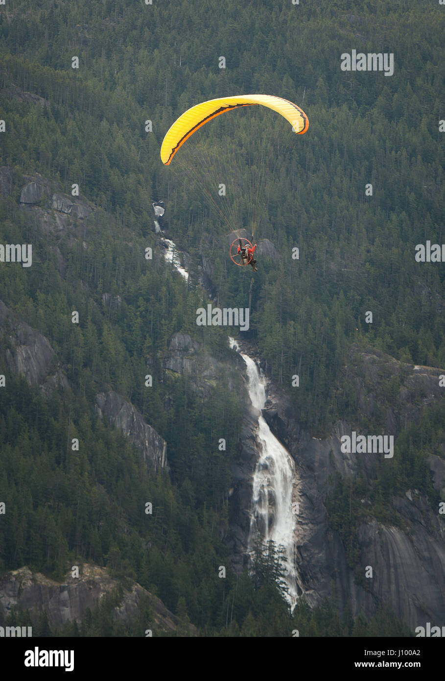 Un uomo vola un parapendio motorizzato o para motore oltre il Capotribù Stawamus e Cascate Shannon. Squamish BC, Canada. Foto Stock