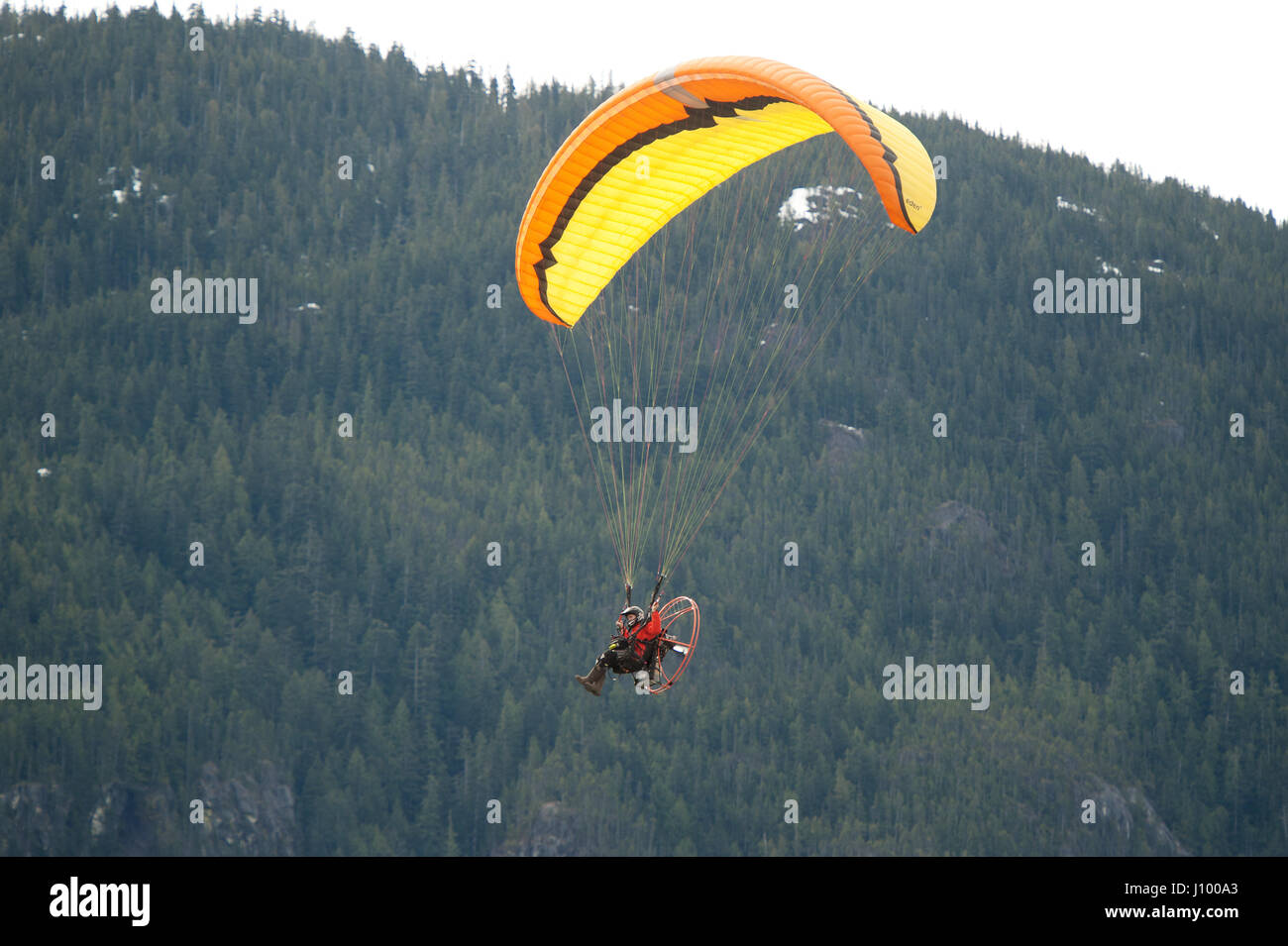 Un uomo vola un parapendio motorizzato o para motore oltre il Capotribù Stawamus e Cascate Shannon. Squamish BC, Canada. Foto Stock