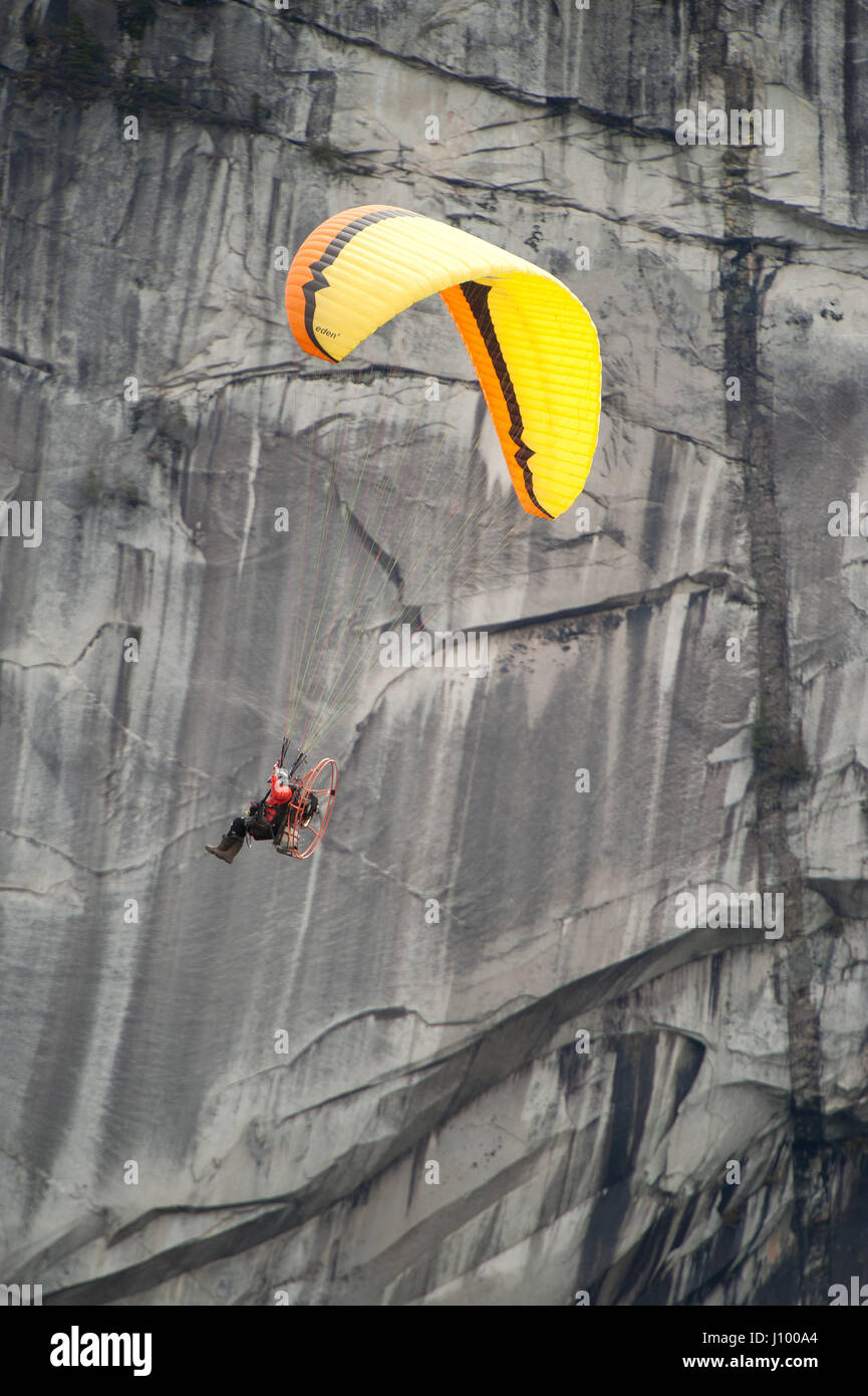 Un uomo vola un parapendio motorizzato o para motore oltre il Capotribù Stawamus e Cascate Shannon. Squamish BC, Canada. Foto Stock