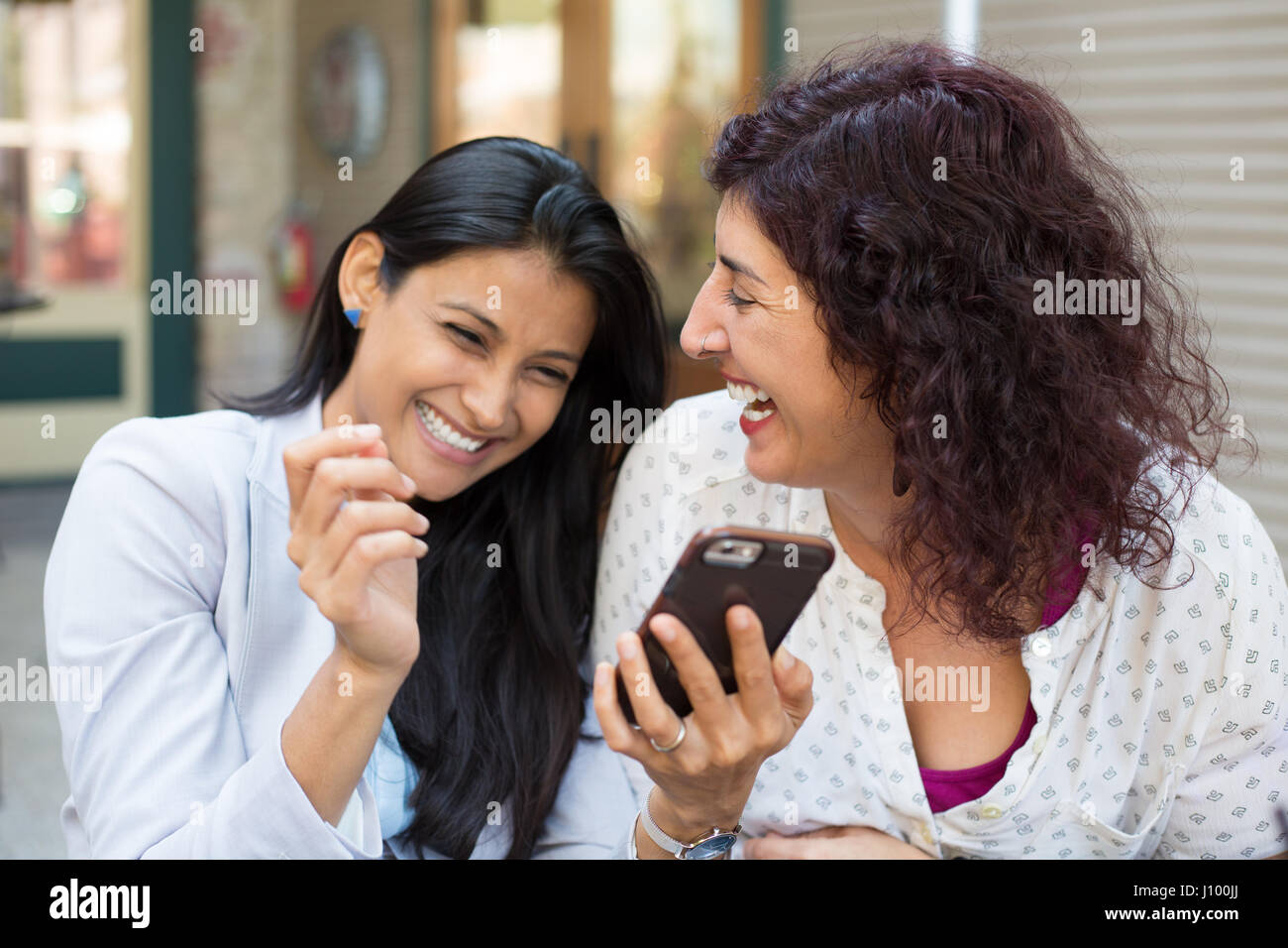 Closeup ritratto di due ragazze sorpreso guardando al telefono cellulare, discutendo Ultime notizie News, la condivisione di momenti intimi, shopping, ridendo a ciò che s Foto Stock