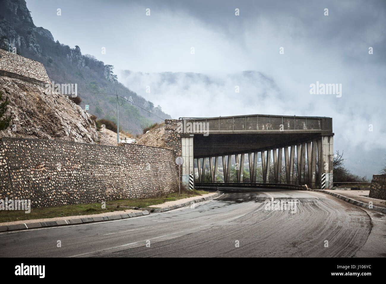 Strada di Montagna di calcestruzzo con struttura a tunnel in nebbioso giorno piovoso, auto rurale Tema Viaggi Foto Stock