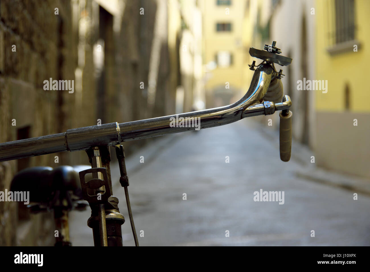 Manubrio di bicicletta dettaglio contro un bokeh Vicolo nel centro di Firenze (Firenze), Toscana, Italia, Europa - il fuoco selettivo sul manubrio Foto Stock