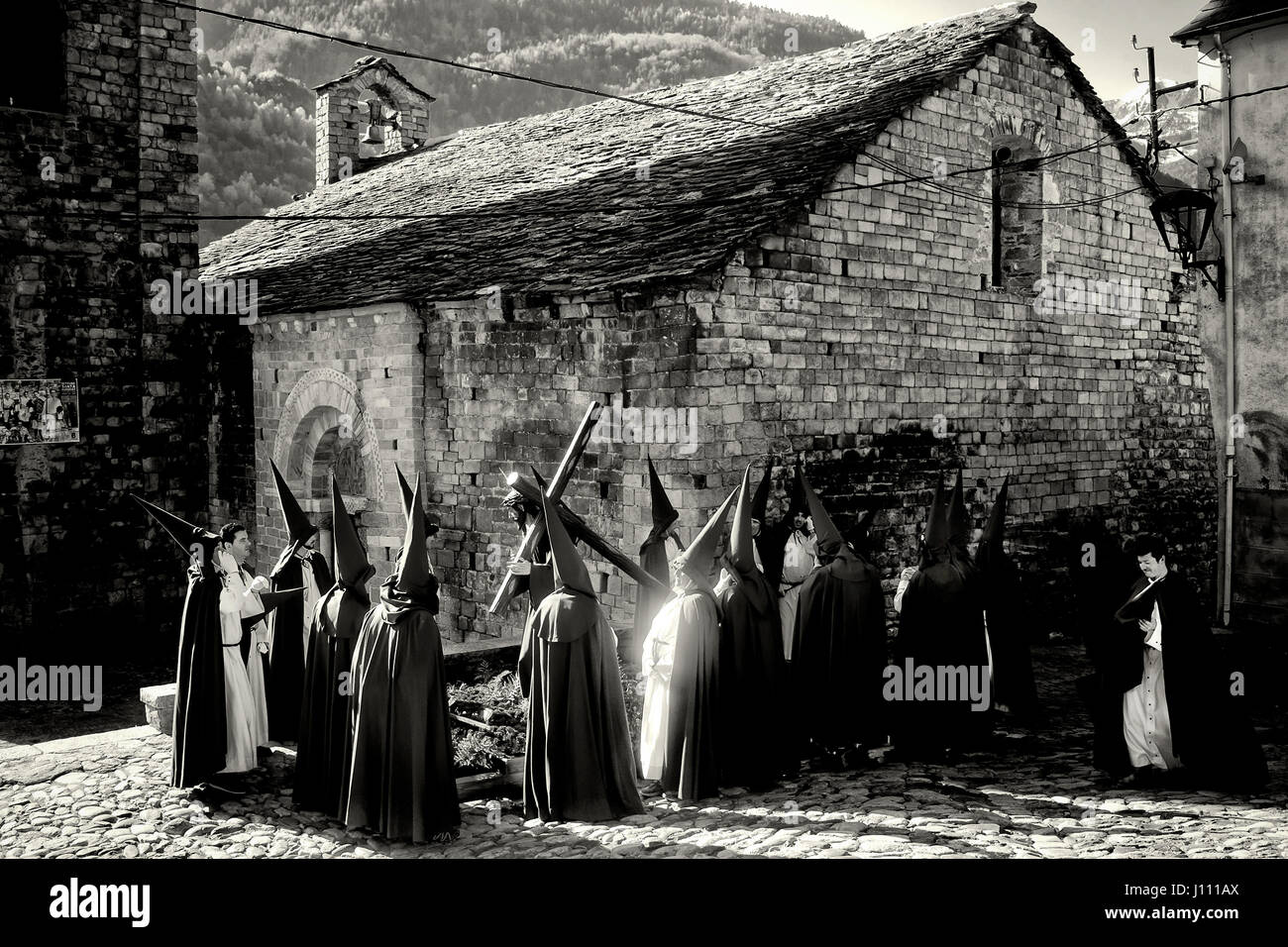 Vicini di Bossost vestito come penitenti rimanere accanto alla chiesa momenti prima di iniziare la processione del Venerdì santo per le strade dei Pirenei Foto Stock