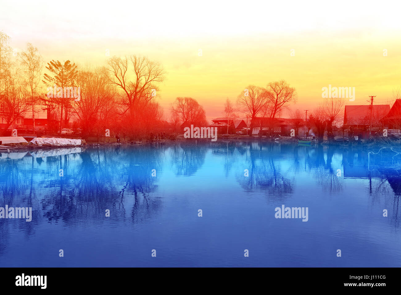 Villaggio russo da un lago al tramonto Foto Stock