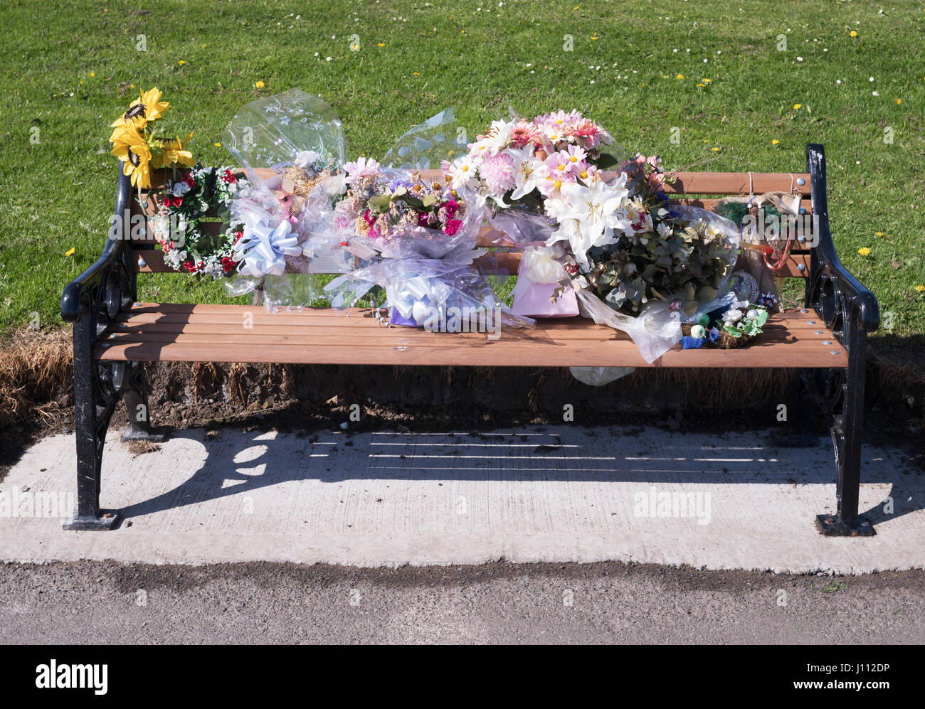 Un memoriale panchina coperta in omaggi floreali, England, Regno Unito Foto Stock