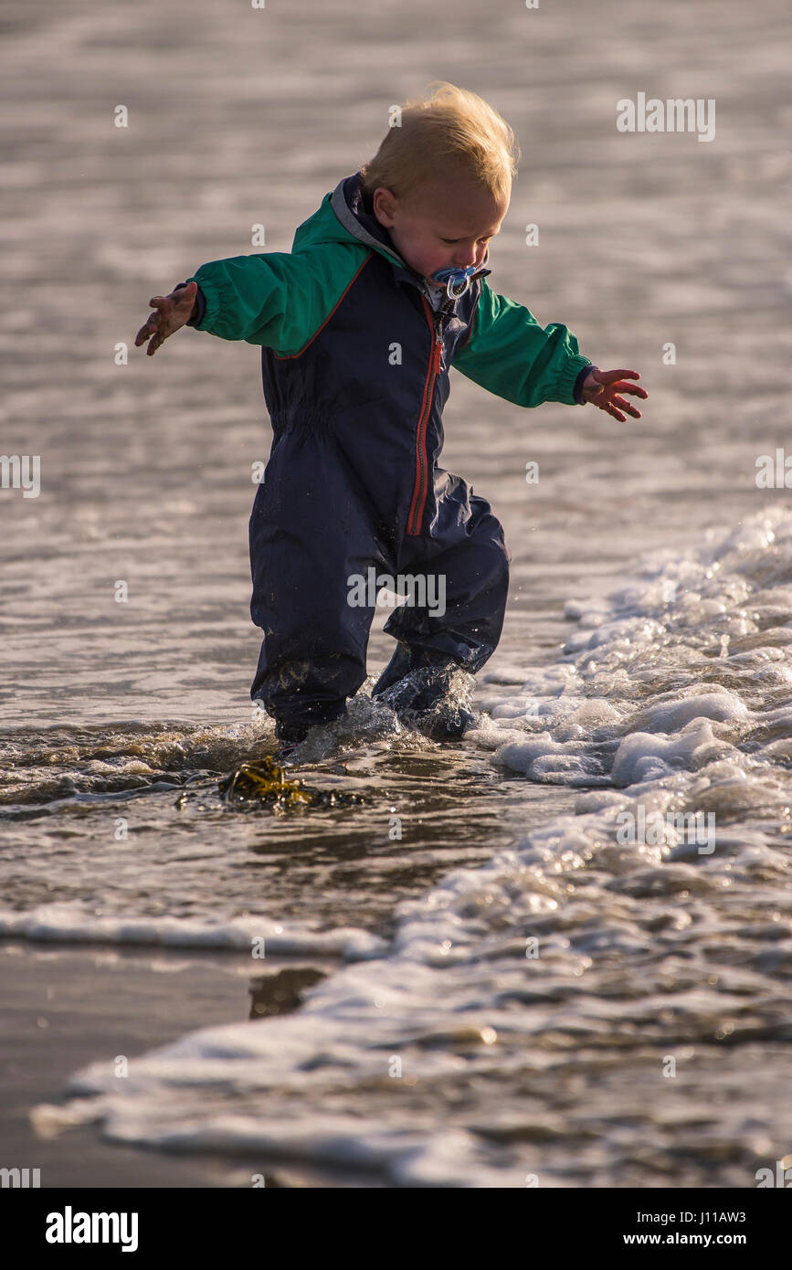 Bambino Toddler giocando Boy Mare litorale eccitato nuova esperienza di spruzzi di apprendimento godendo di divertimento Turismo Fistral Beach Foto Stock