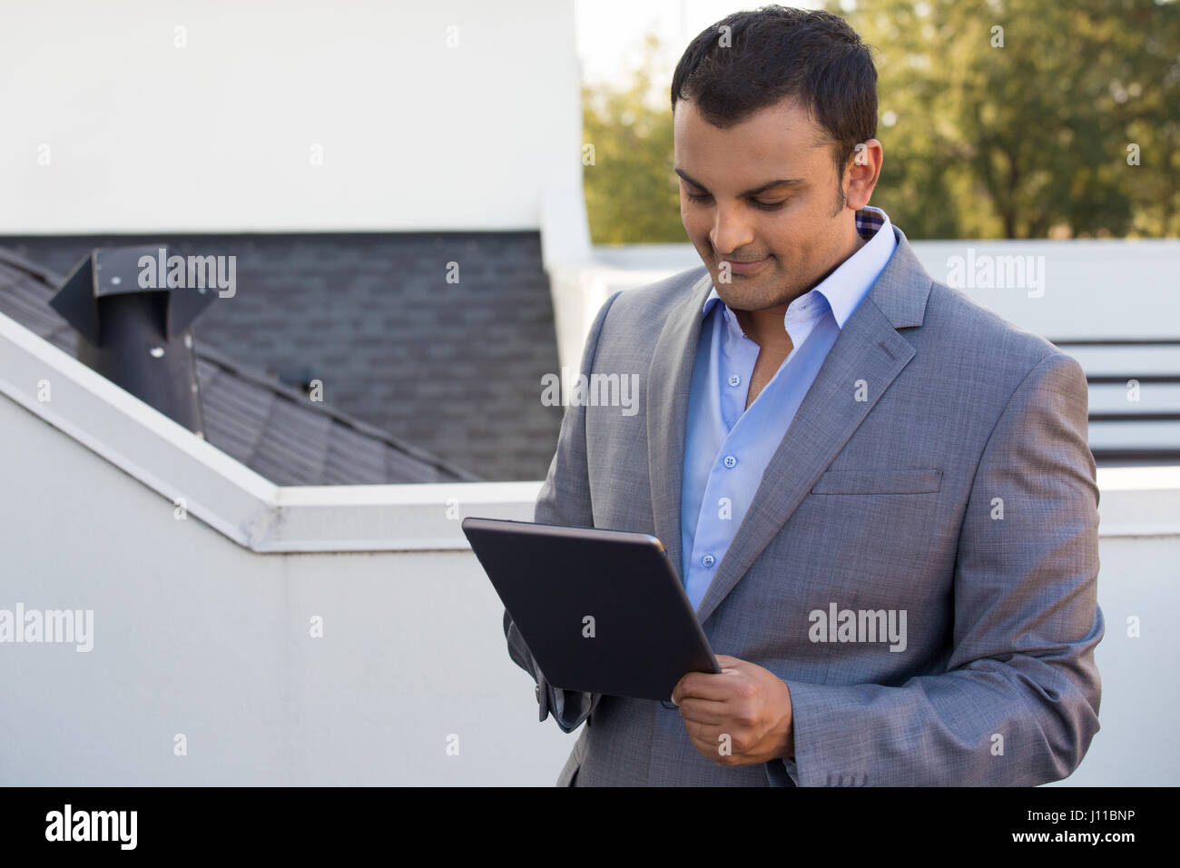 Closeup ritratto, uomo in abito grigio blazer doing business su tablet, fuori all'aperto sullo sfondo Foto Stock