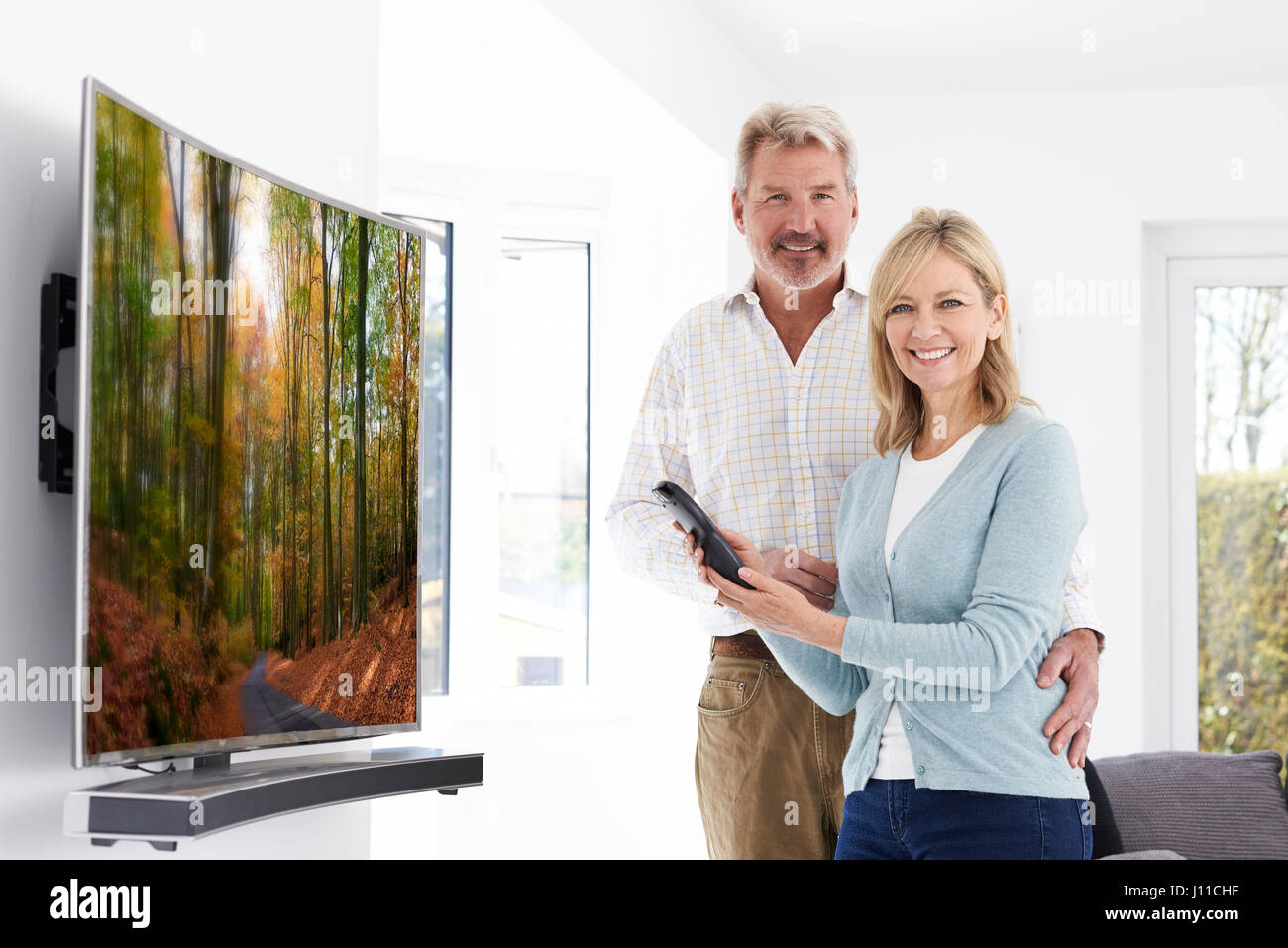 Coppia matura con il nuovo schermo curvo la televisione a casa Foto Stock
