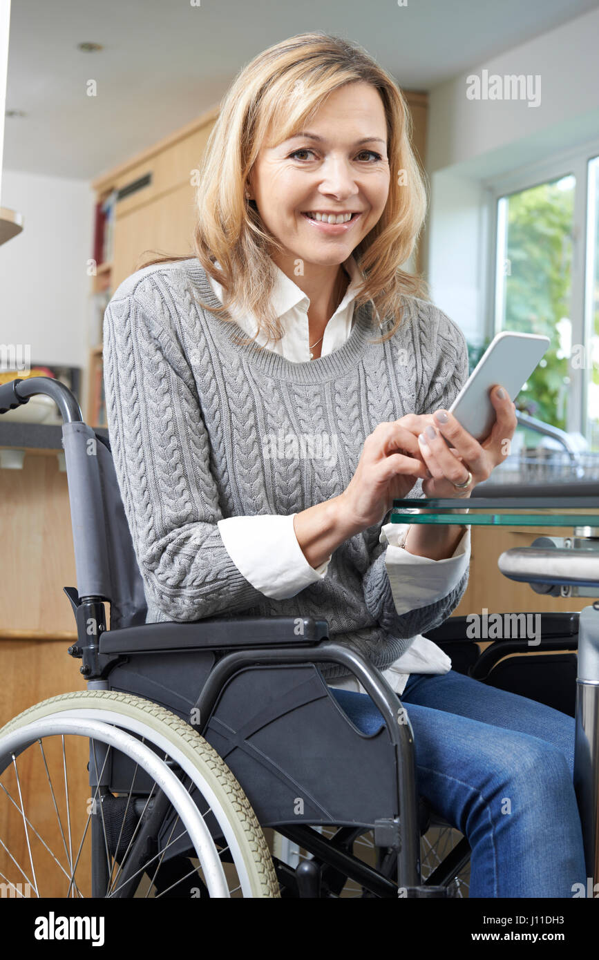 Donna disabile in carrozzella sms sul cellulare a casa Foto Stock