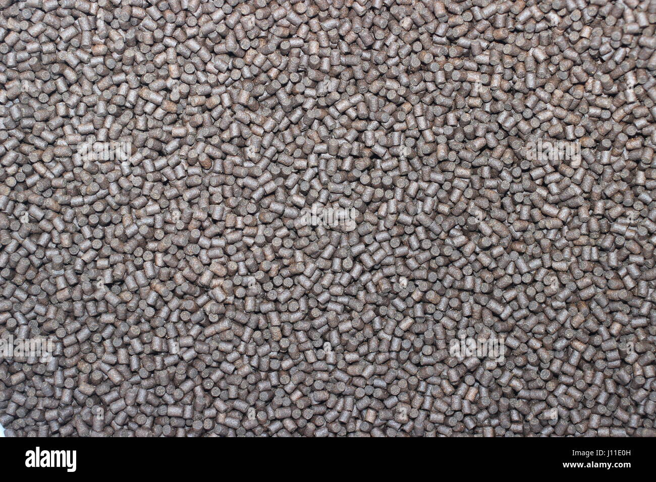 Una immagine di sfondo di colore marrone scuro granulati di mangimi per animali. Foto Stock