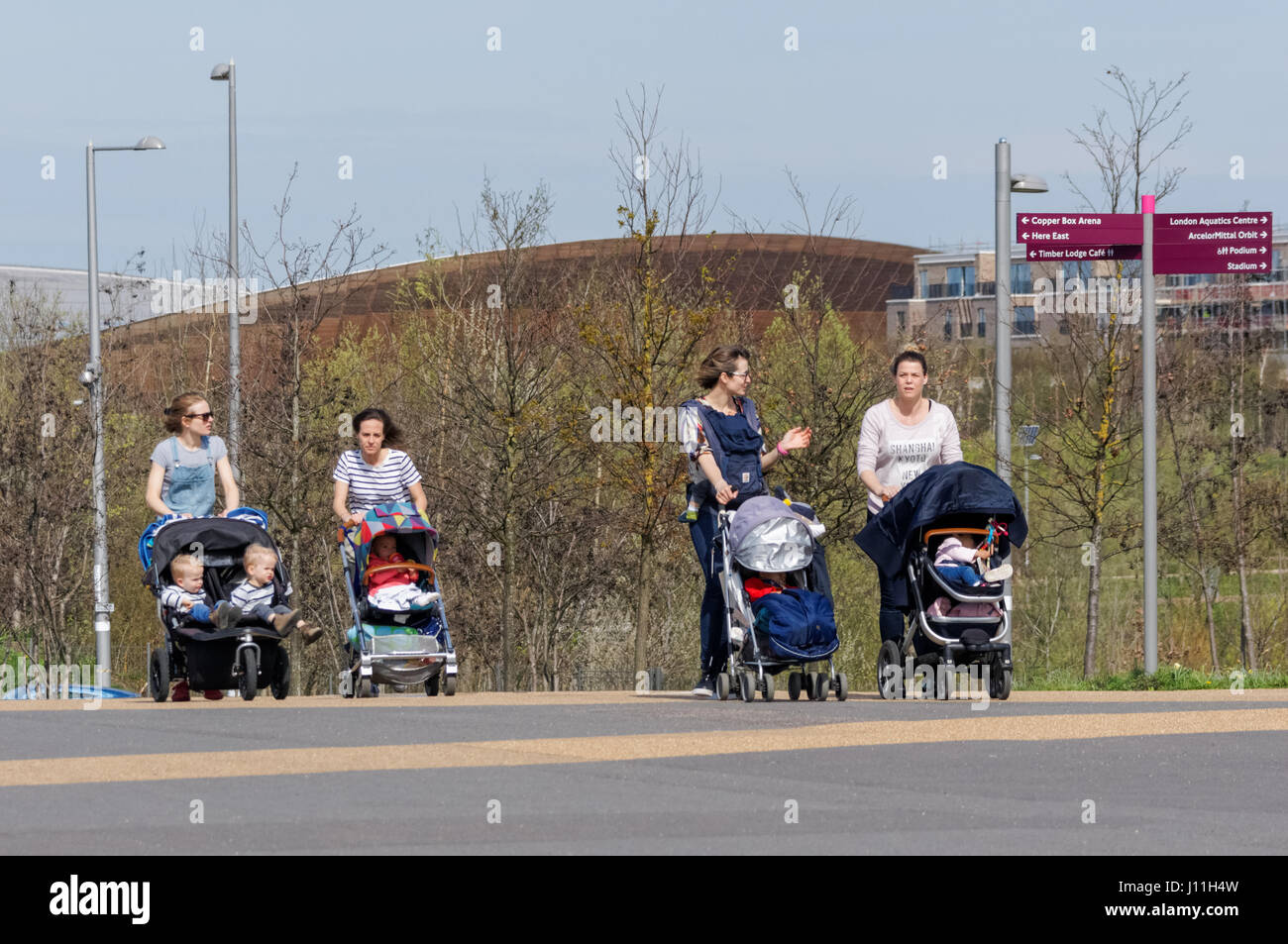 Le giovani donne a piedi con i loro bambini in presso la Queen Elizabeth Olympic Park, Londra England Regno Unito Regno Unito Foto Stock