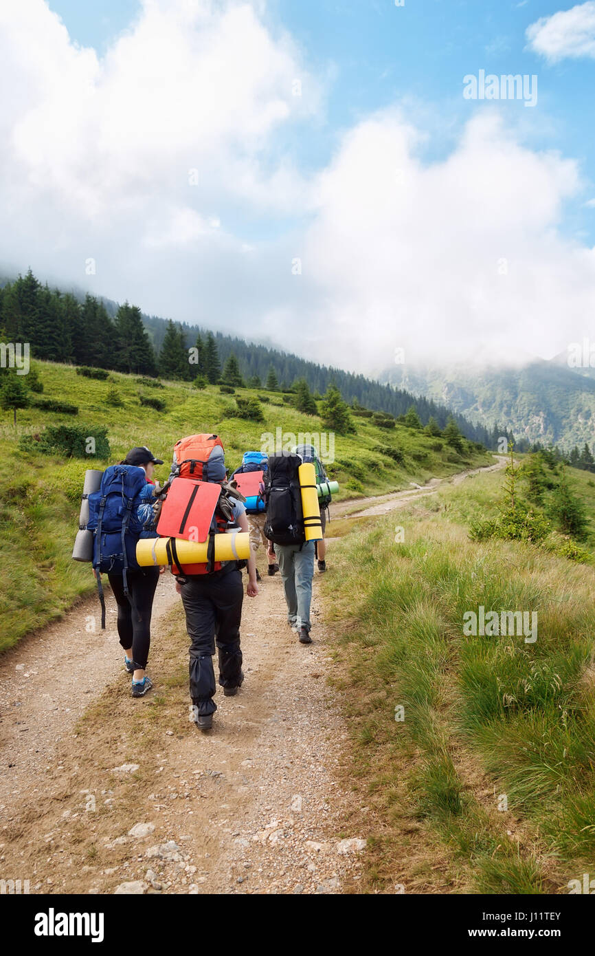 Gruppo di escursionisti con zaini su un sentiero attraverso la foresta in montagna. Vacanze attive. I turisti del trekking sulla strada sterrata. Uno stile di vita sano, adve Foto Stock