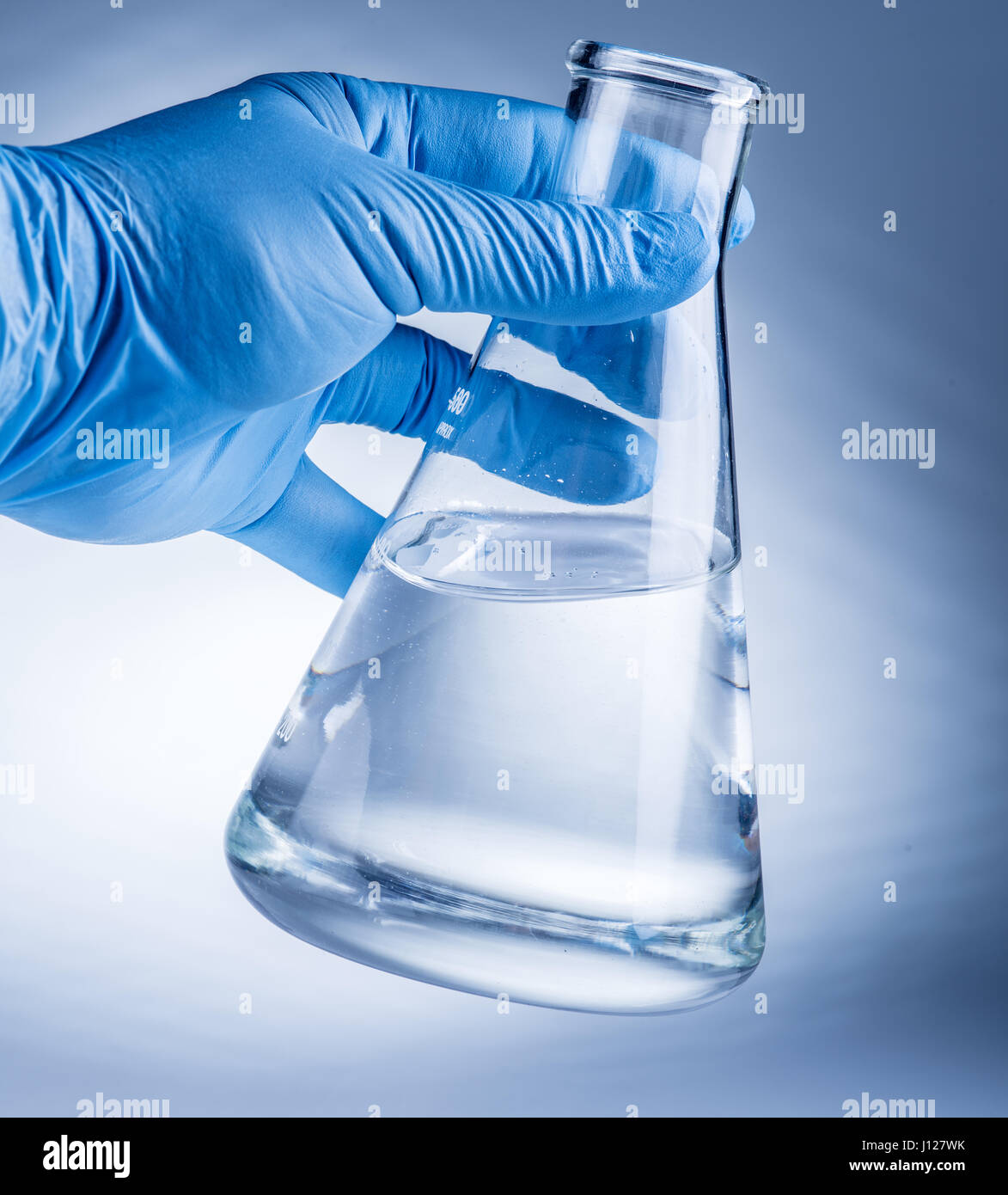 Bicchiere da laboratorio in analyst la mano nel guanto di plastica. Foto Stock