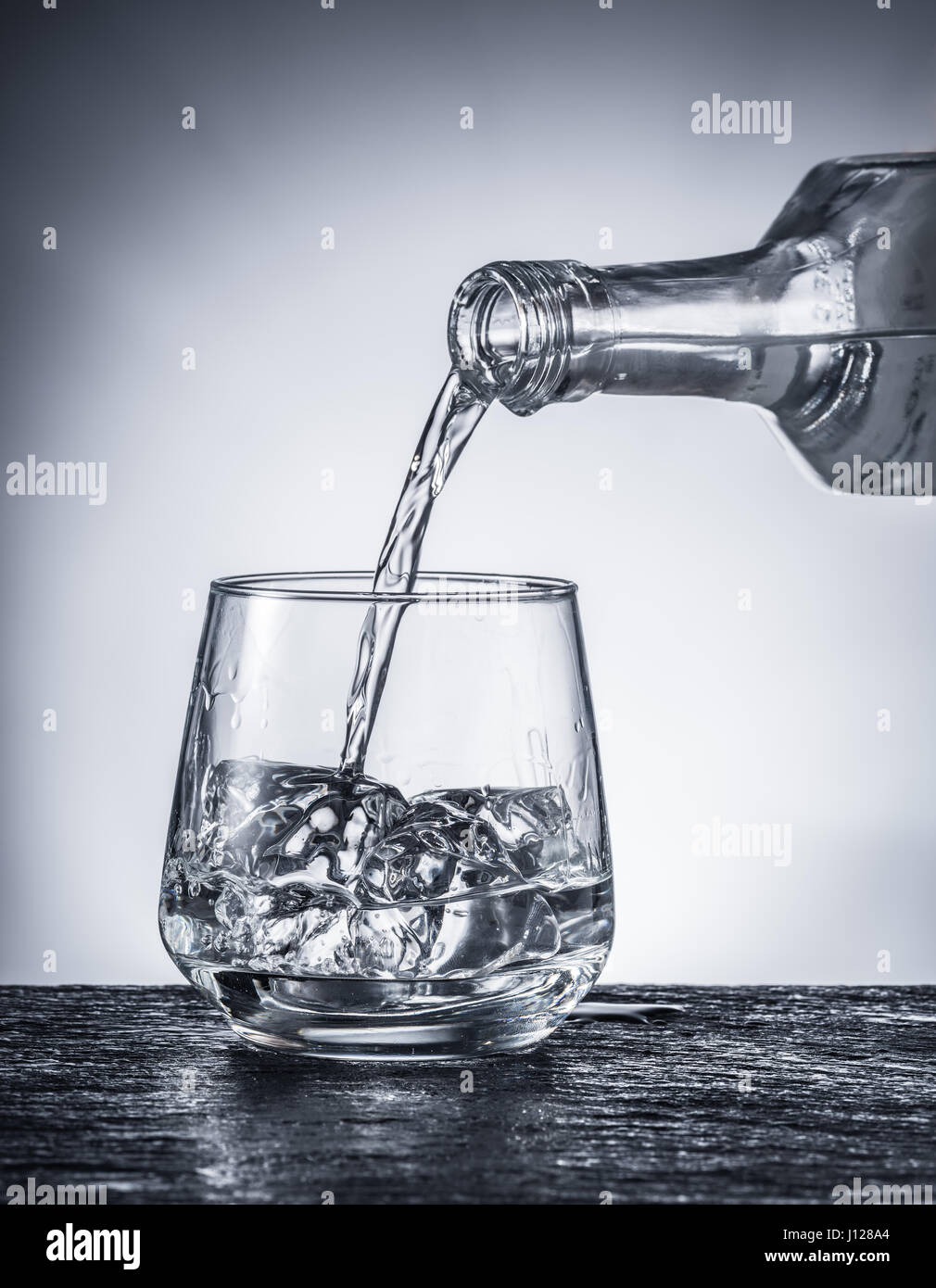 Versando l'alcol in un bicchiere. Immagine monocromatica. Foto Stock