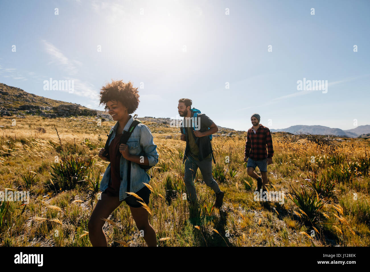 Gruppo di persone a piedi attraverso la campagna. Felice di giovani uomini e donne escursionismo insieme su un giorno d'estate. Foto Stock