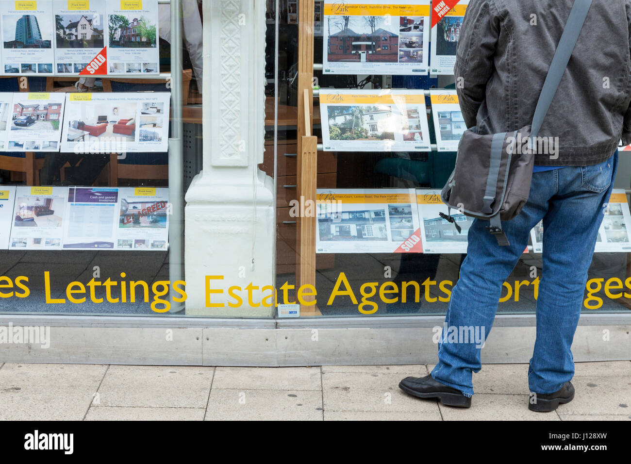Uomo che guarda in agente immobiliare della finestra in corrispondenza di case e altri immobili in vendita e in affitto, Nottingham, Inghilterra, Regno Unito Foto Stock