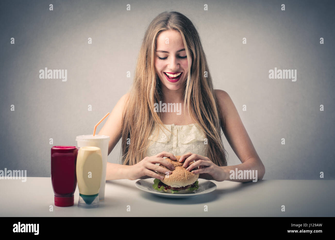 Giovane donna bionda mangiare hamburger Foto Stock