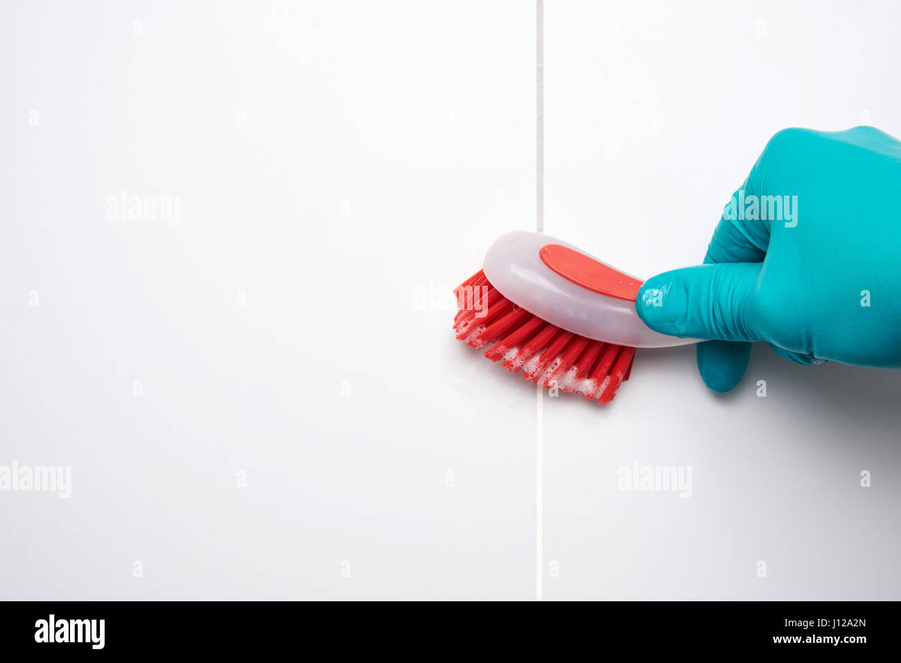 Maschio di mano con pennello rosso la pulizia del bagno piastrelle e lacune. Prima e dopo l'effetto. Foto Stock