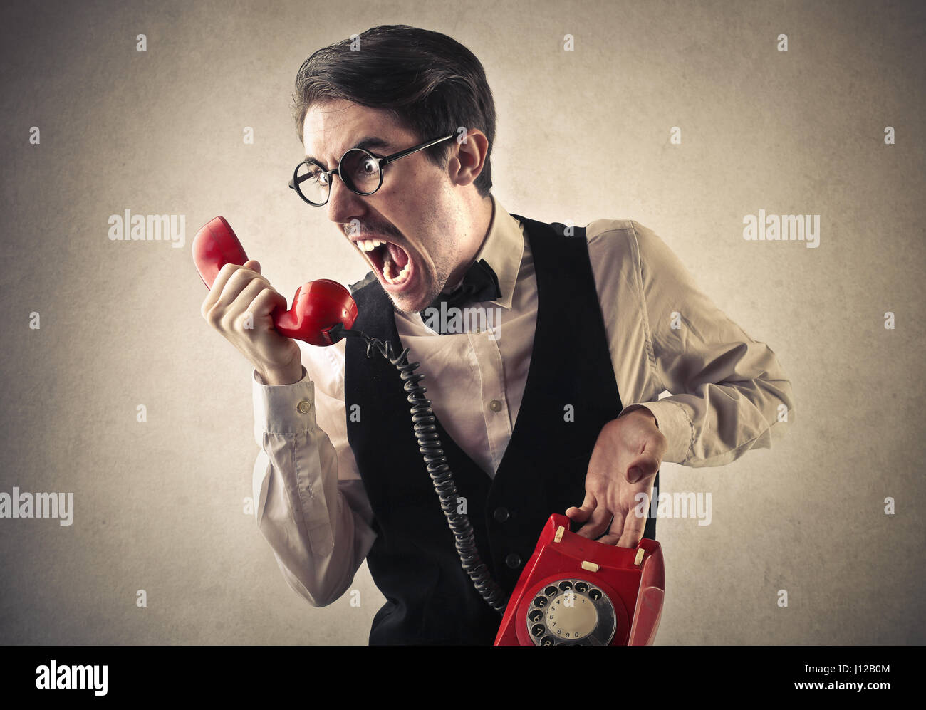 L'uomo urla con retro rosso telefono Foto Stock