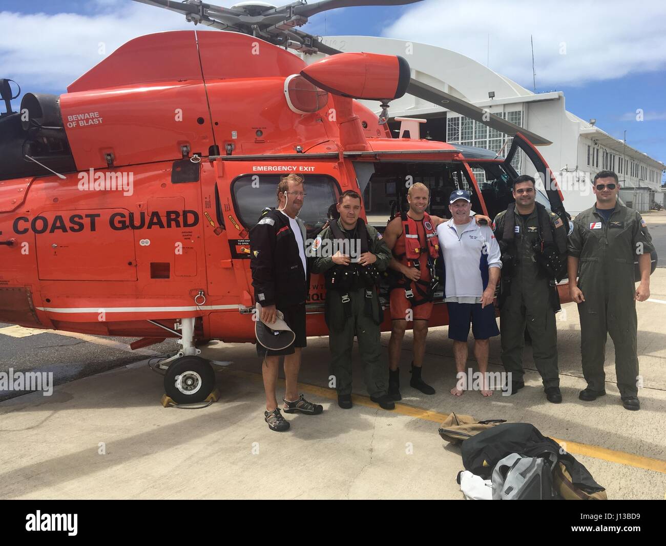 L'equipaggio di un Coast Guard MH-65 Delfino elicottero dalla stazione aria Borinquen tiene una foto con salvato naviganti, Kirk Plender dal New Hampshire e John Boone dalla Carolina del Sud, in seguito al salvataggio dei diportisti provenienti da una zattera di Aprile 13, 2017. I diportisti sono stati costretti ad abbandonare la 62-piede nave a vela Ocean Quest che affondò in argento banche, circa 80 miglia nautiche a nord o a Puerto Plata, Repubblica Dominicana. Foto Stock