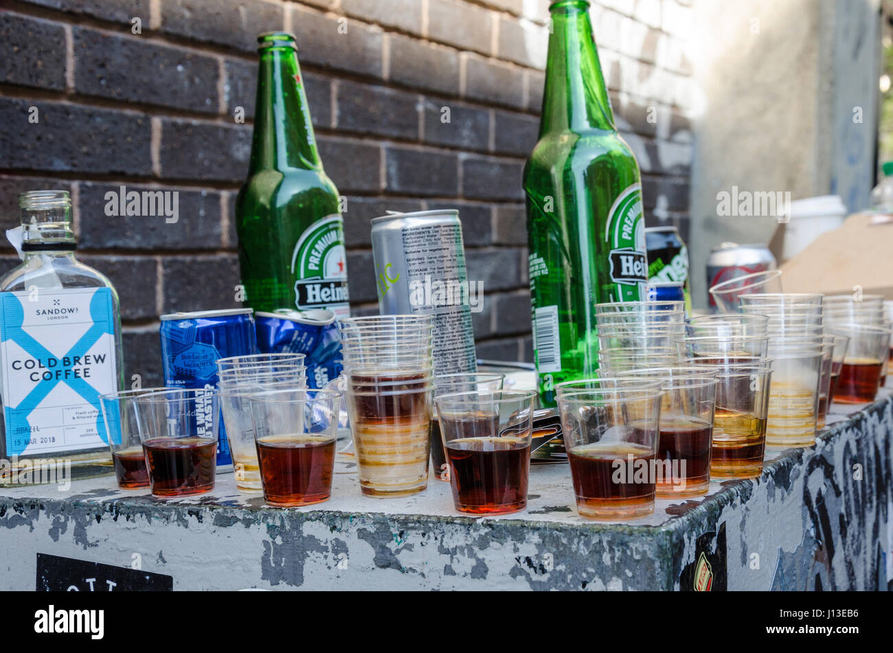 Svuotare le bottiglie di birra e plastica bicchierini abbandonata su una sporgenza al di fuori in strada. Foto Stock