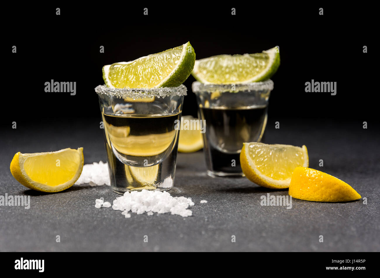 Messicano bevanda alcolica tequila con sale e succo di limone o lime nero sul tavolo di pietra Foto Stock