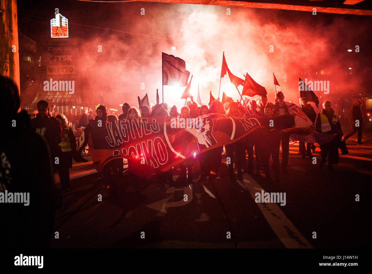 I manifestanti marzo con striscioni con clear anti-capitalista messaggi mentre altri fire fino flares nel loro modo alla abbattuto "casa della gioventù" Ungdom Foto Stock