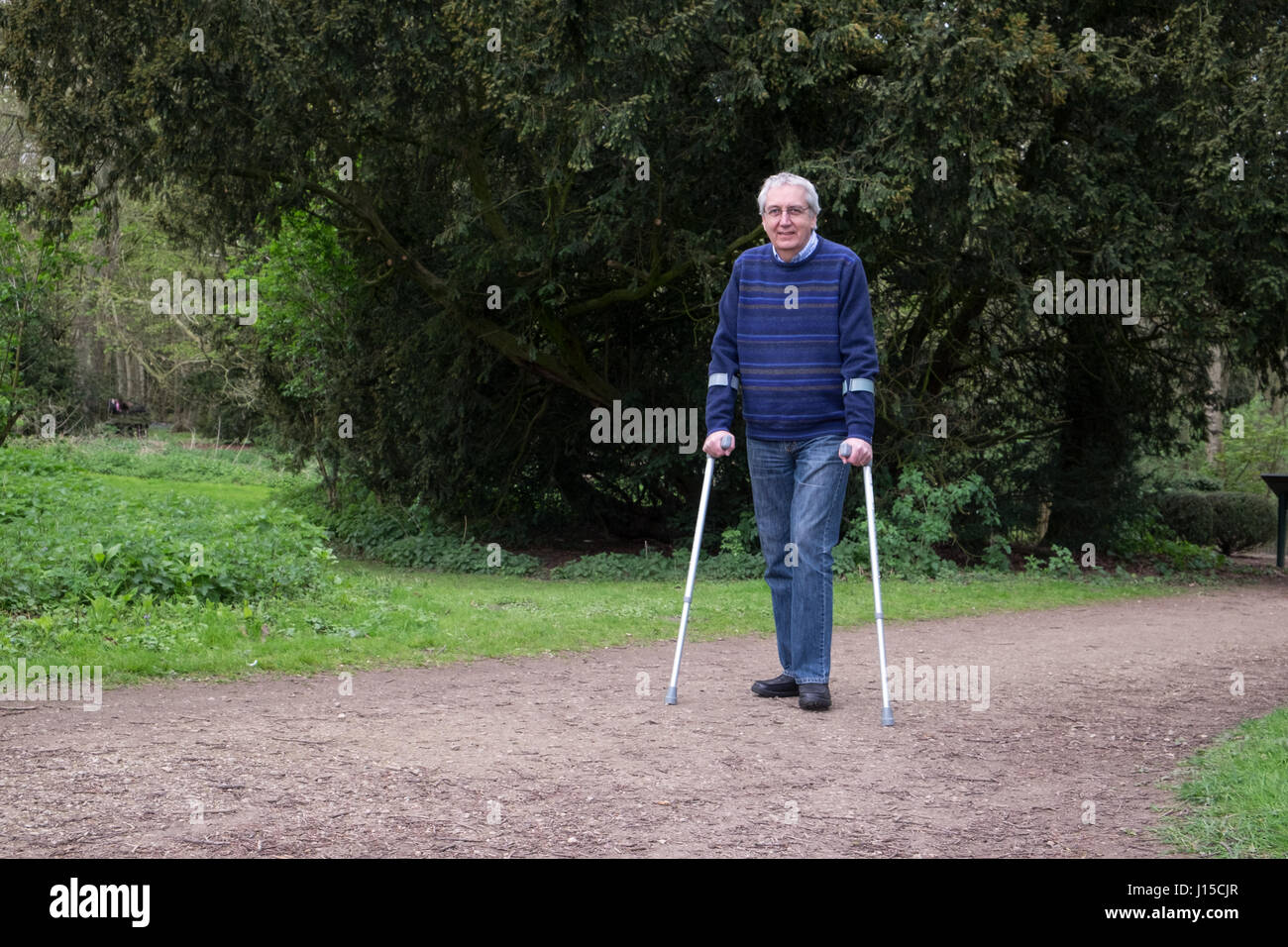 Senior uomo a camminare con le stampelle Foto Stock