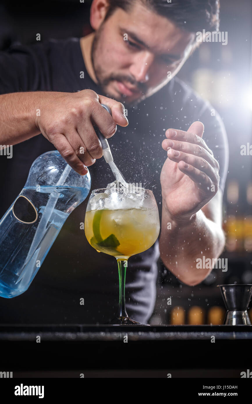 Il barista è versando acqua di soda, egli sta preparando un cocktail di mango Foto Stock