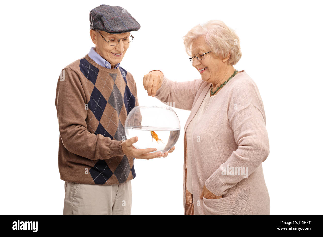 Uomo anziano tenendo un recipiente con un pesciolino e una donna anziana per l'alimentazione isolata su sfondo bianco Foto Stock