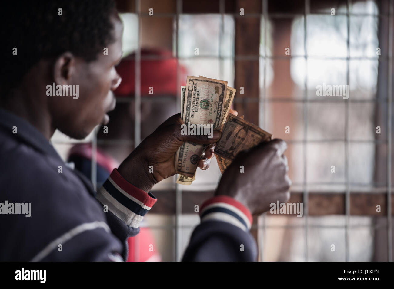 Un ex membro della milizia esamina valuta statunitense dato a lui come parte del suo pacchetto di smobilitazione per Goma nella Repubblica democratica del Congo Foto Stock