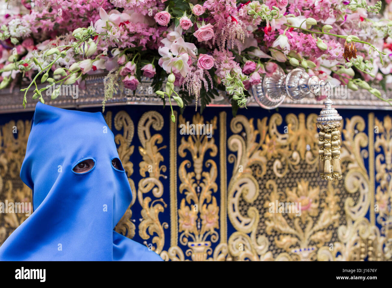 Nazareno che va con la mano sulla manigueta il trono in una processione della Settimana Santa. Non indossare capirote e la maschera cade allentato dalla testa, Foto Stock